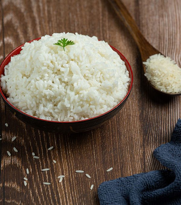 White rice is placed in a cup on the wooden floor.